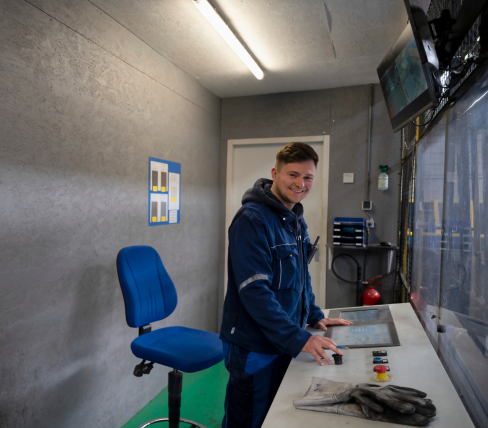 Danylo works as an operator in a technical workspace with a desk and monitors, visibly proud of his workplace