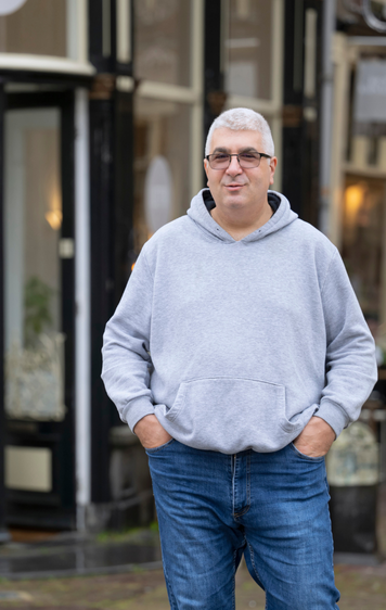 Kandidaat poseert in grijze hoodie in een historische binnenstad.