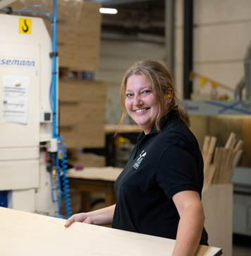 Smiling operator working with wooden panels in a woodworking company