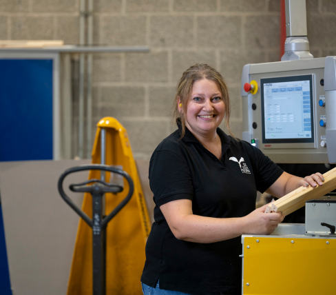 Katarzyna is smiling while working at a machine in a production environment, happy with the job she found through PDZ