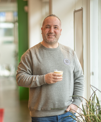Man smiling with a cup of coffee at the office